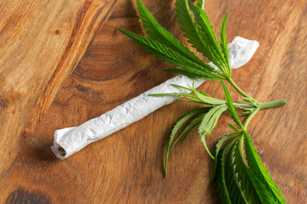 joints and marijuana leaves on a wooden table 