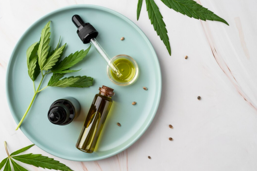 A CBD oil dropper on a turquoise plate with cannabis leaves, an open bottle, and scattered seeds against a white backdrop.